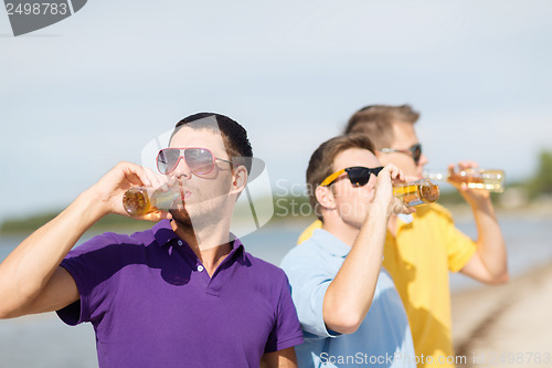 Image of friends on the beach with bottles of drink