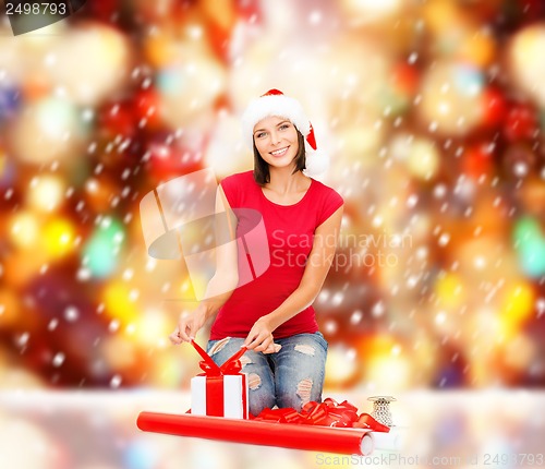 Image of smiling woman in santa helper hat with gift box