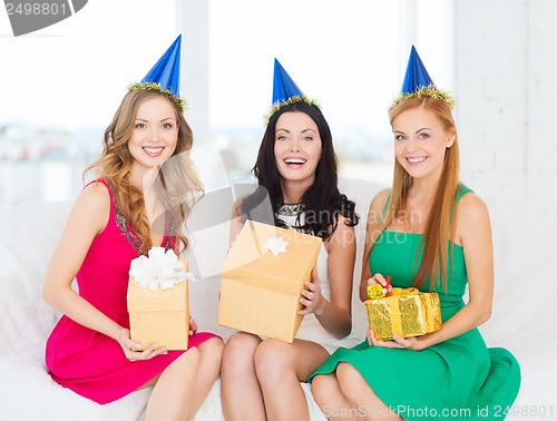 Image of three smiling women in blue hats with gift boxes