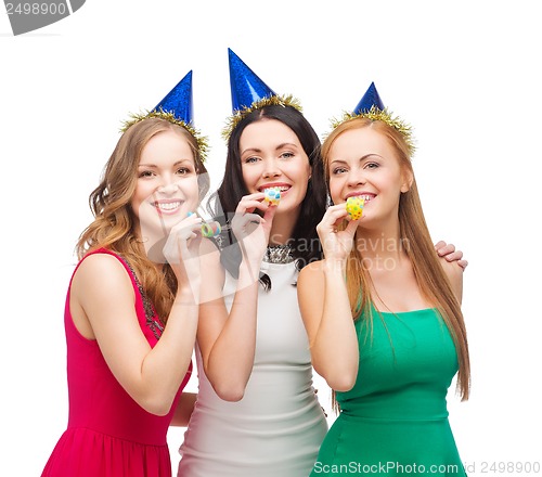 Image of three smiling women in hats blowing favor horns