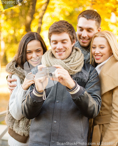 Image of group of friends with photo camera in autumn park