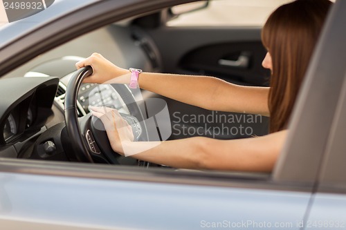 Image of woman driving a car with hand on horn button