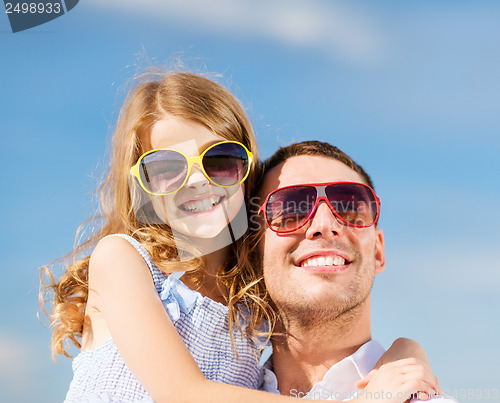 Image of happy father and child in sunglasses over blue sky