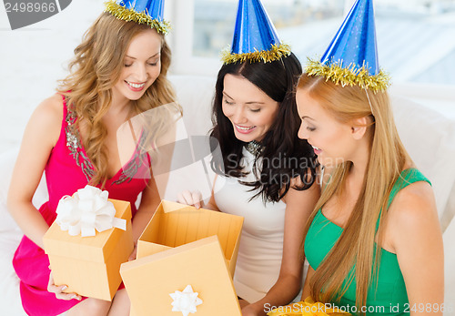 Image of three smiling women in blue hats with gift boxes