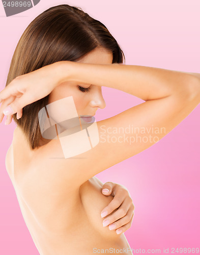 Image of woman checking breast for signs of cancer