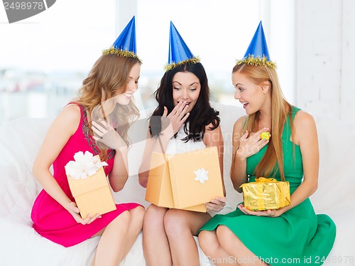 Image of three smiling women in blue hats with gift boxes