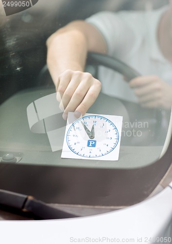 Image of man placing parking clock on car dashboard