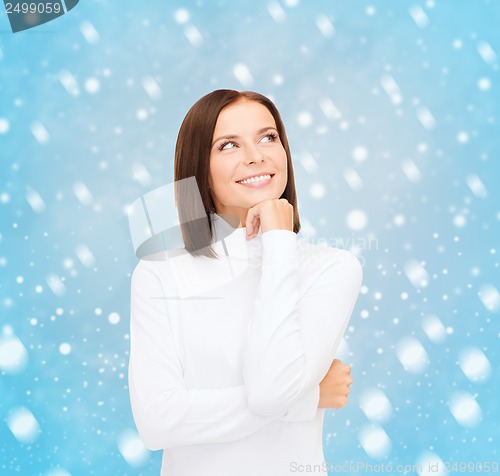 Image of thinking and smiling woman in white sweater