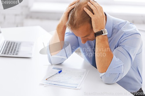 Image of stressed businessman with papers at work