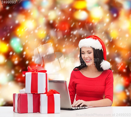 Image of woman with gift boxes and laptop computer