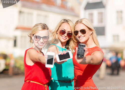 Image of beautiful girls with smartphones in the city