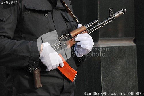 Image of hands in white gloves with a Kalashnikov 