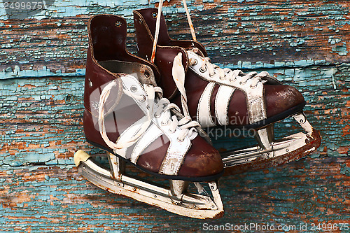 Image of vintage pair of mens  ice skates on a wooden wall