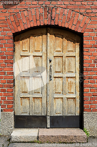 Image of large yellow door in brick wall