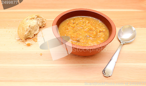 Image of Half-eaten bread roll with a bowl of vegetable soup