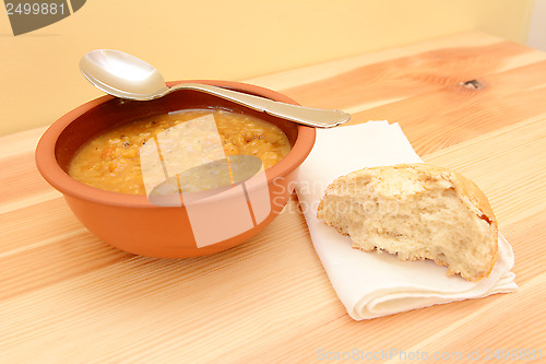 Image of Bowl of soup, with a half-eaten bread roll on a serviette 