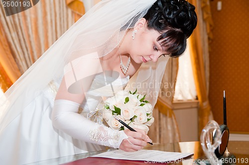 Image of Pretty bride signing document