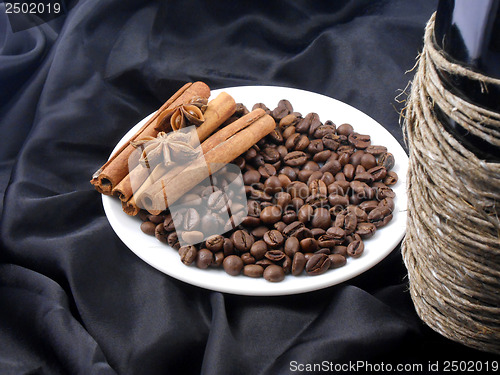 Image of Champagne bottle, coffee beans, cinnamon and star anis on black material