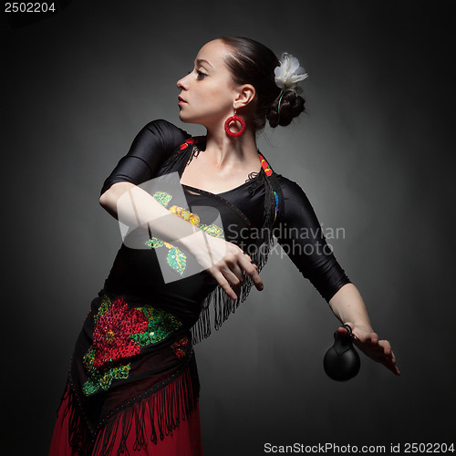 Image of young woman dancing flamenco with castanets on black