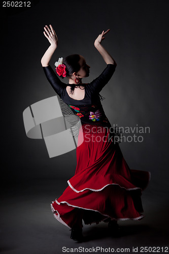Image of young woman dancing flamenco on black