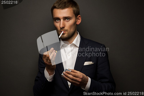 Image of portrait of handsome businessman with cigarette on black