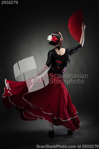 Image of young woman dancing flamenco on black