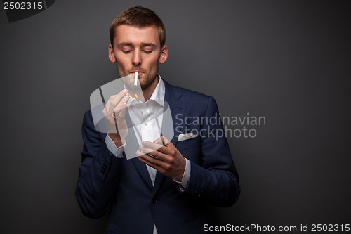 Image of portrait of handsome businessman with cigarette on black