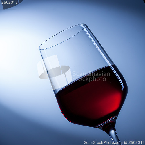 Image of red wine in glass on blue