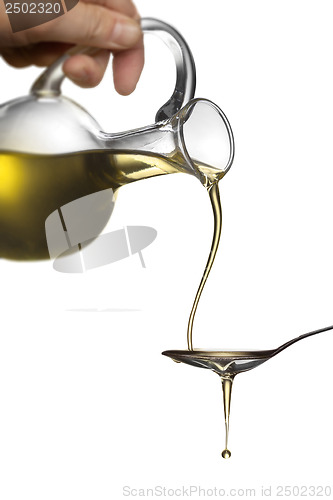 Image of Pouring oil from jar on spoon isolated on white