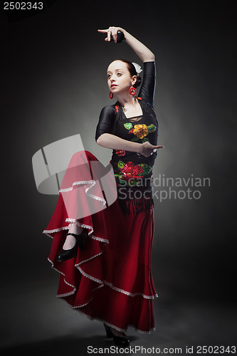 Image of young woman dancing flamenco with castanets on black