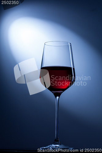 Image of red wine in glass on blue
