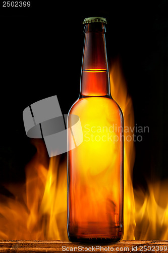 Image of Beer bottle in fire on black