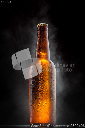 Image of Cold beer bottle with drops, frost and vapour on black