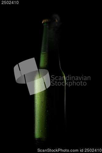 Image of Green beer bottle with drops and open cup on black