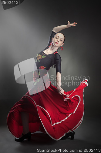 Image of young woman dancing flamenco on black