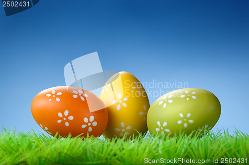 Image of Color easter eggs in the grass on blue