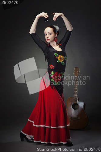 Image of young woman dancing flamenco with castanets on black