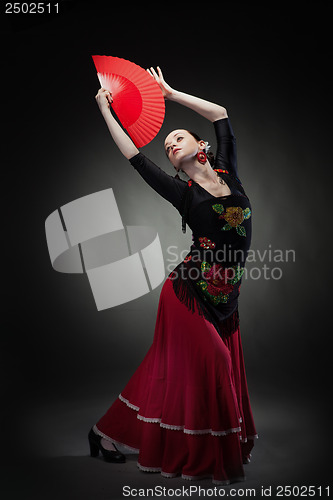 Image of young woman dancing flamenco on black