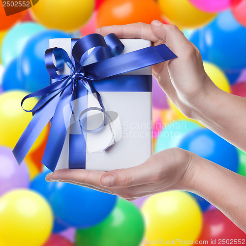 Image of Hands holding gift in package with blue ribbon
