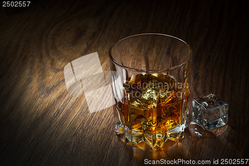 Image of Whiskey with ice in glass on the wood