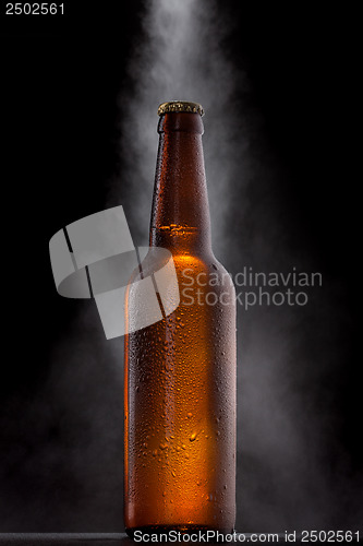 Image of Cold beer bottle with drops, frost and vapour on black