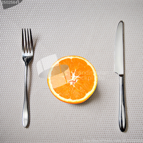 Image of Healthy breakfast - fresh orange with knife and fork