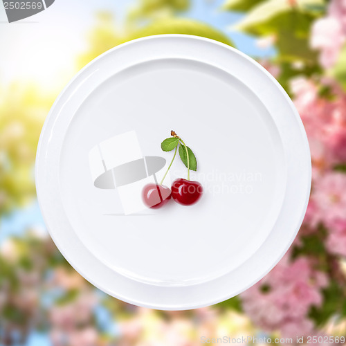 Image of Cherry on white plate against sakura flowers