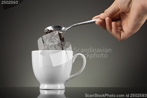 Image of tea pour out into white cup on grey