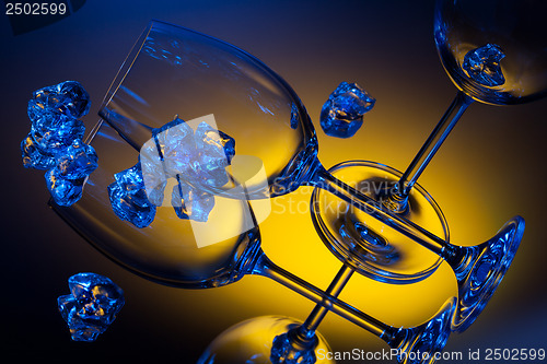 Image of ice and empty wineglasses on color background