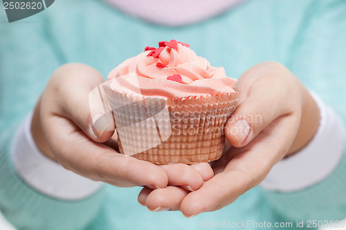 Image of Woman holding a pink cupcake on white