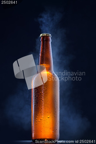 Image of Cold beer bottle with drops, frost and vapour on black