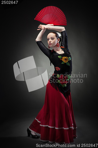 Image of young woman dancing flamenco on black