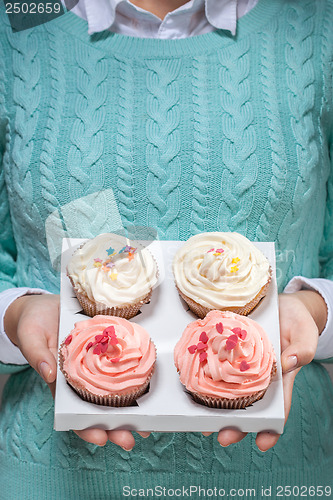 Image of woman holding cupcakes in hands