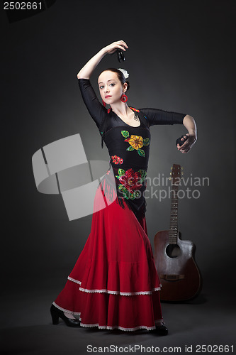 Image of young woman dancing flamenco with castanets on black